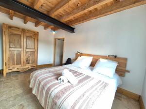 Schlafzimmer mit einem Bett mit weißer Bettwäsche und einer Holzdecke in der Unterkunft Chez Bob - Grange de Charme in Olloix