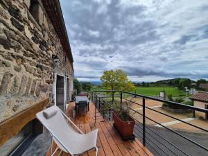 ein Balkon mit zwei weißen Stühlen an einem Gebäude in der Unterkunft Chez Bob - Grange de Charme in Olloix