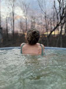 a person in the water in a hot tub at River Camp in Lembuži
