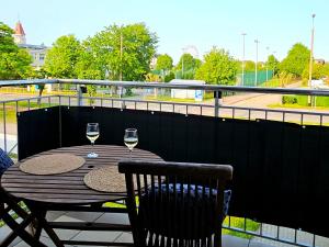 a wooden table with two glasses of wine on a balcony at Apartament 1000-lecia in Władysławowo