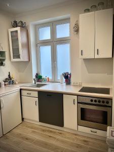 a kitchen with white cabinets and a sink and a window at Kwatera Prywatna Maja in Sopot