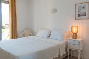 a white bedroom with a bed and a window at HOTEL CAMPOMORO in Belvédère-Campomoro