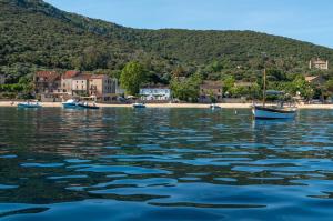 a boat floating on the water near a beach at HOTEL CAMPOMORO in Belvédère-Campomoro