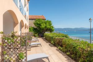 a row of chairs on a sidewalk next to the water at HOTEL CAMPOMORO in Belvédère-Campomoro