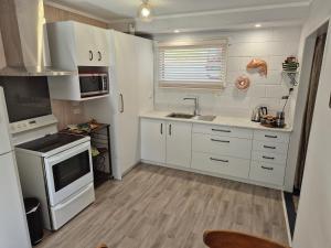 a kitchen with white cabinets and a sink at Bonnie Doon on the Thames coast in Thames