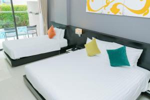 two beds with colorful pillows in a room at Beachfront and Deluxe Pool Access Patong Phuket in Patong Beach