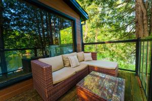 a wicker couch sitting on a screened porch with a table at Le Chalet Brun, jacuzzi en bord de lac in Saint Adolphe D'Howard