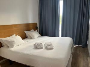 a large white bed with two towels on it at Sintra Sol - Apartamentos Turisticos in Sintra