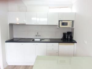 a white kitchen with a sink and a microwave at Sintra Sol - Apartamentos Turisticos in Sintra