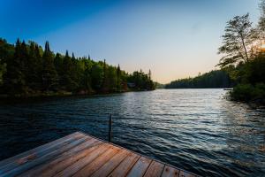 a wooden dock on a lake with trees at Le Chalet Brun, jacuzzi en bord de lac in Saint Adolphe D'Howard
