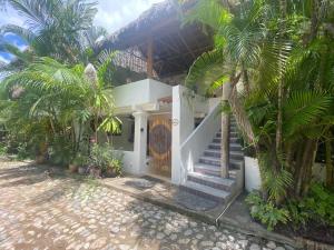 a white house with palm trees in front of it at Villa Sophie 3BR3BA Beachfront Terrace Heated Pool New Listing in Sayulita