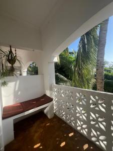 a balcony with a bench and a palm tree at Siri Beach Lodge in Nungwi