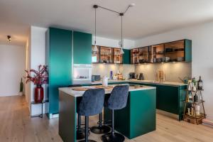 a kitchen with green cabinets and bar stools at Les Terrasses de Lavaux-2 Appartement de Luxe avec Vue Panoramique et Piscine" in Chexbres