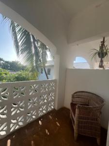 a room with a balcony with a chair and a palm tree at Siri Beach Lodge in Nungwi