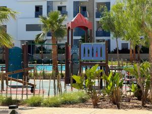 un parque infantil frente a un edificio con palmeras en Rincón del Mar, en Martil