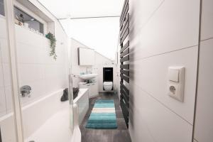 un bagno bianco con lavandino e WC di Ring48 City Living - modernes Wohnen mit Wohlfühlambiente mitten im Stadtzentrum - vollausgestattete Küche, Bad mit Duschbadewanne, Parkplatz a Bayreuth