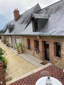a brick house with a gray roof and a patio at Le gîte La Colonge, cosy et charmant in Glos-sur-Lisieux