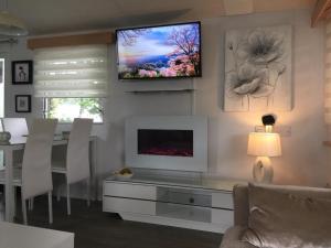 a living room with a table and a tv on the wall at Dunes Views in Prestatyn