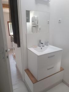 une salle de bain blanche avec un lavabo et un miroir dans l'établissement Maisonnette dans hameau provençal, à Cabriès