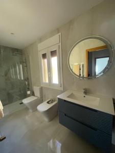 a bathroom with a sink and a toilet and a mirror at Chalet Avenida El Barraco Avila in El Barraco