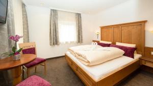 a bedroom with a bed with a wooden headboard and a table at Jungmann Apartments in Ischgl