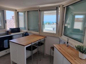 a small kitchen with windows and a wooden table at Attichetto monolocale vista mare terrazzatissimo Asterspace in Anzio
