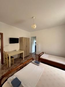 a room with two beds and a table and a desk at Niks Apartments in Ksamil