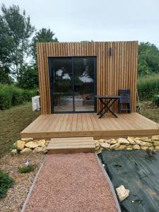 a tiny house with a wooden deck and a table at Le Refuge Des Loups in Biziat