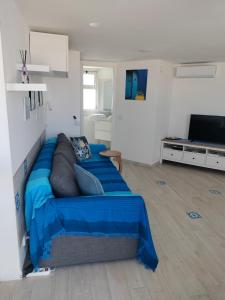 a living room with a couch with a blue blanket at Attichetto monolocale vista mare terrazzatissimo Asterspace in Anzio
