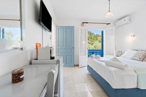 a bedroom with a bed and a desk and a television at Hotel Selini in Agios Nikitas