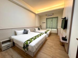 a hotel room with two beds and a television at Travel Happiness Homestay in Huxi