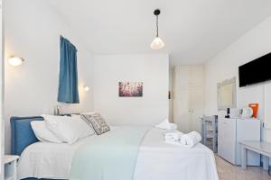 a white bedroom with a bed and a tv at Hotel Selini in Agios Nikitas