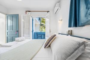 a white bedroom with a bed and a blue door at Hotel Selini in Agios Nikitas