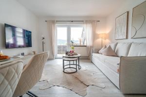 ein Wohnzimmer mit einer weißen Couch und einem Tisch in der Unterkunft Gemütliche Ferienwohnung mit Berg und Alpsee Panorama im Allgäu in Immenstadt im Allgäu