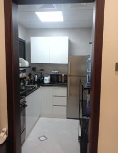 a small kitchen with white cabinets and appliances at Cozy Beautiful Private Room with Shared Washroom in Ajman 