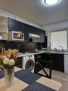 eine Küche mit schwarzen Schränken und einer Vase mit Blumen auf dem Tisch in der Unterkunft 2х комнатная in Zhezdi