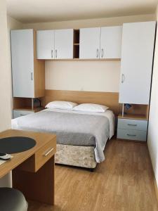 a bedroom with a bed with white cabinets and a desk at Apartments Slijepcevic in Hvar
