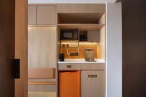 a kitchen with an orange refrigerator and a microwave at Home2 Suite by Hilton Hengshui Taocheng in Hengshui