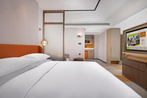 a bedroom with a white bed and a flat screen tv at Home2 Suite by Hilton Hengshui Taocheng in Hengshui