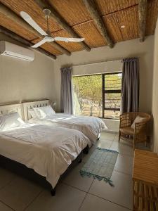 a bedroom with a bed with a ceiling fan and a window at Ingonyama Rest in Marloth Park +50 photos
