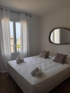 a bedroom with a large white bed with a mirror at Appartement neuf, proche des plages et centre ville in Saint-Florent