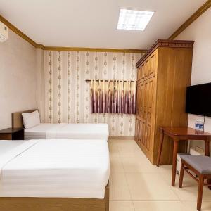 a bedroom with two beds and a desk and a television at LuxuryK&T Hotel-Near Bùi Viện Walking Street in Ho Chi Minh City