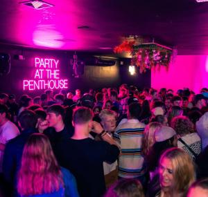 una multitud de personas en una habitación con luces rosas en Modern living in central town, en Stellenbosch