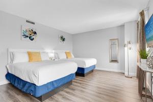 two beds in a room with white walls and wood floors at Fabulous Angled Oceanfront Suite! CR1701 in Myrtle Beach +28 photos