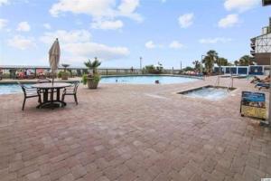 a patio with a table and an umbrella next to a pool at Fabulous Angled Oceanfront Suite! CR1701 in Myrtle Beach