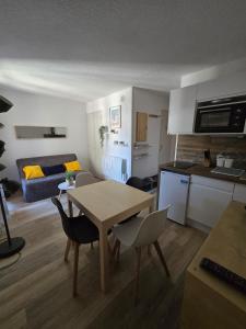 a small kitchen and living room with a table and chairs at Appartement chaleureux in Risoul