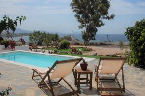 a couple of chairs and a swimming pool at Aegean Pearl in Áyios Dhimítrios