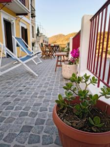 a patio with chairs and potted plants and a table at Lirenou Scala Vista in Symi