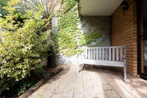a white bench sitting on the side of a house at Bright and Beautiful Near the Gorge with Parking in Royal Park
