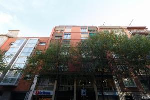 un edificio alto de ladrillo rojo con árboles delante de él en Apartamento Guillermo Tell, en Barcelona